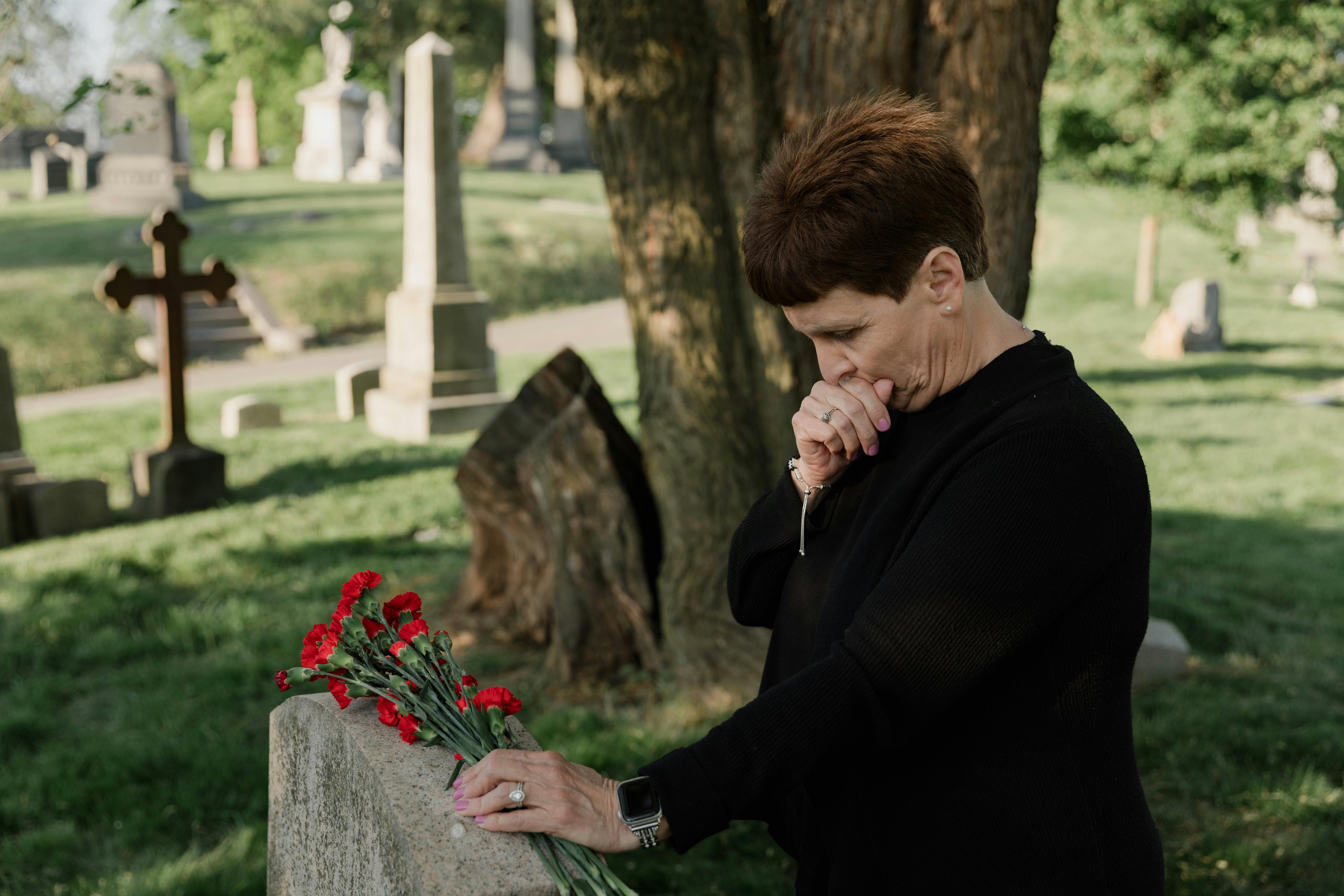 Two individuals searching for a grave in a cemetery, looking at maps and headstones.